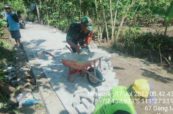 Read more about the article Kerja Bakti, Serda Wahyu Bantu Warga Pasang Paving