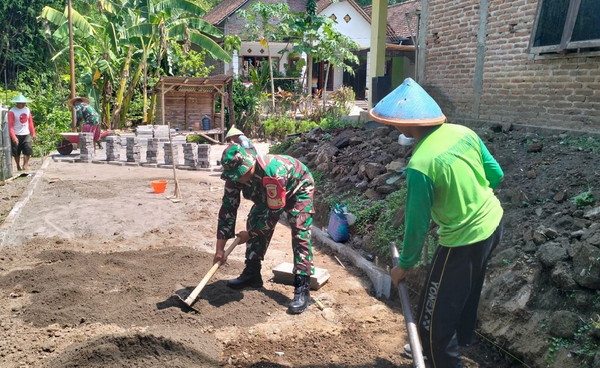 You are currently viewing Tumbuhkan Semangat Gotong Royong, Babinsa Bantu Pasang Paving Blok